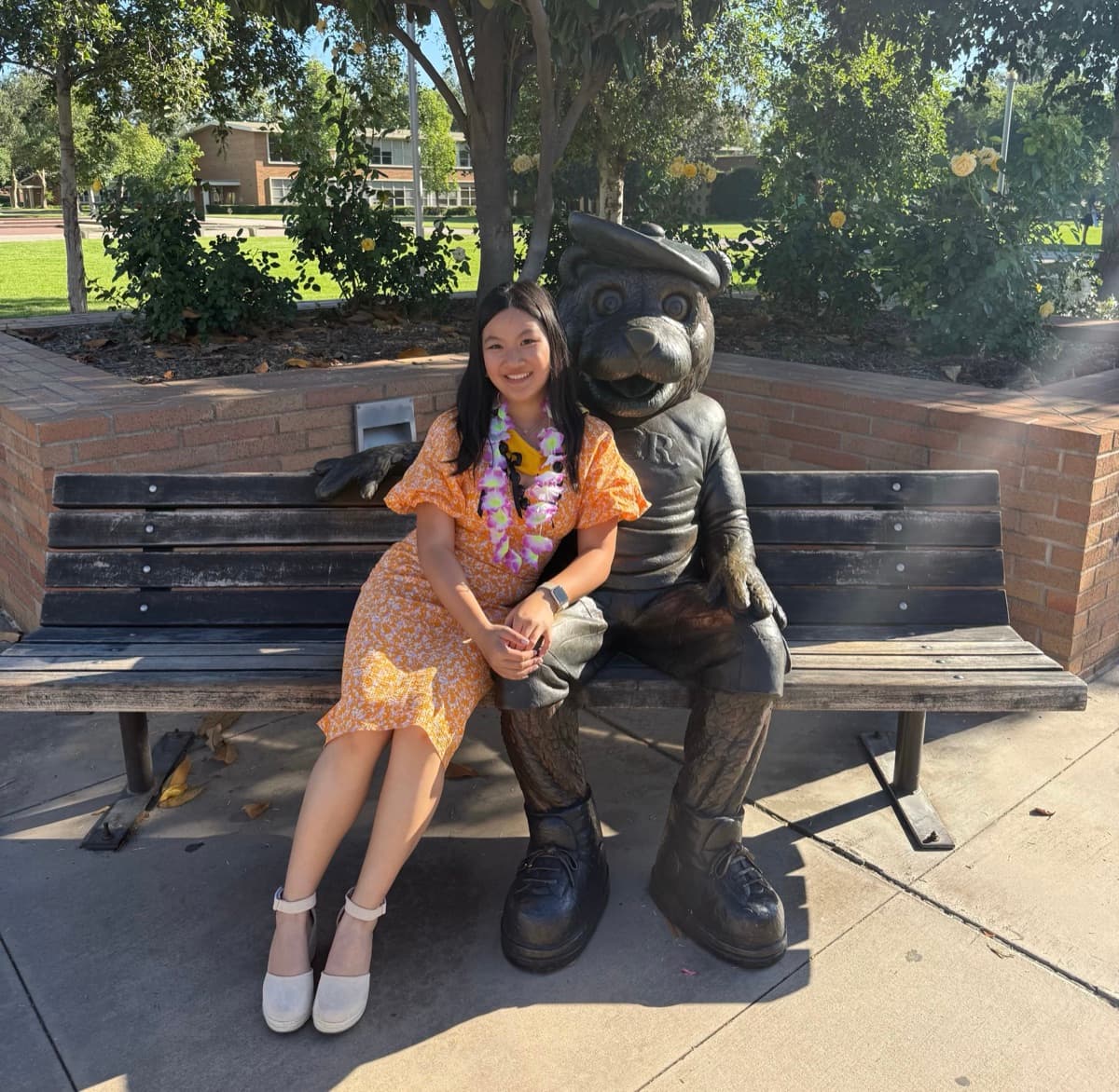Ruoxi Zhao sitting on a bench next to the Scotty the Bear statue at UC Riverside